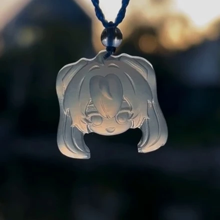 Hatsune Miku pendant D37B hanging from a blue cord, with a clear bead above the smiling face