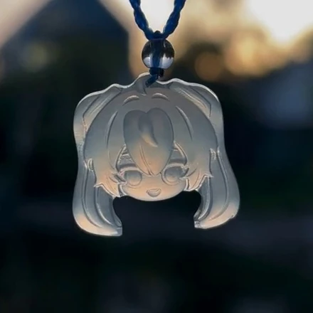 Front view of Hatsune Miku pendant D37B, showing carved eyes, a smile and twin tails