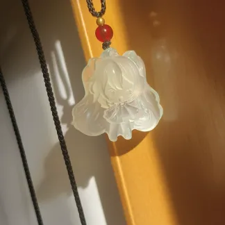 Hatsune Miku pendant 3A46 hanging in sunlight, with a winking figure, twin tails and a red bead